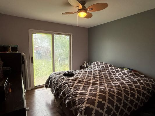 Bedroom with bed, fan, and sliding door.