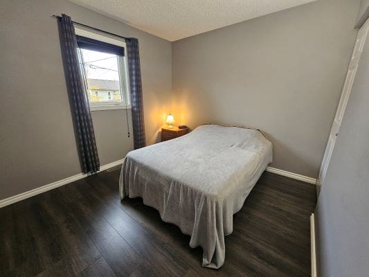 Simple bedroom with bed and nightstand lamp.