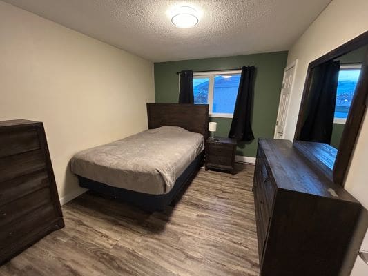 Bedroom with bed, dressers, and window.