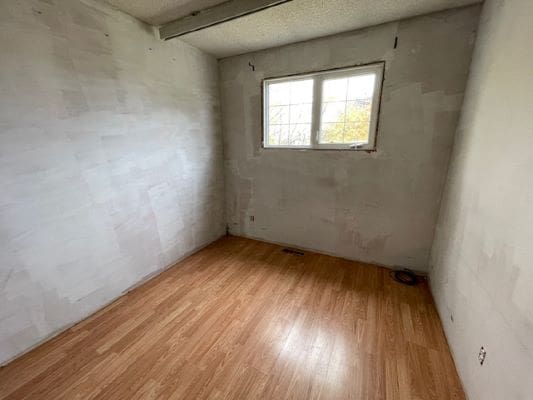 Empty room with wooden floor and window.