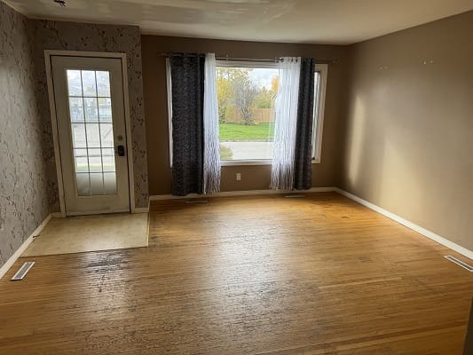 Empty room with wooden floor and window.