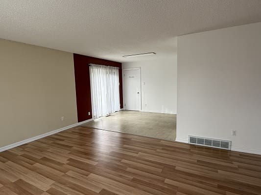 Empty room with wooden and carpeted floors.