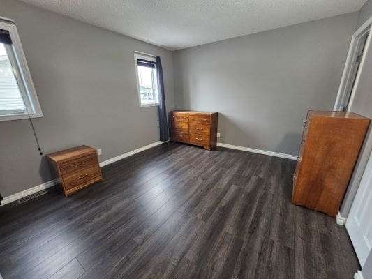 Empty room with wooden furniture and windows.
