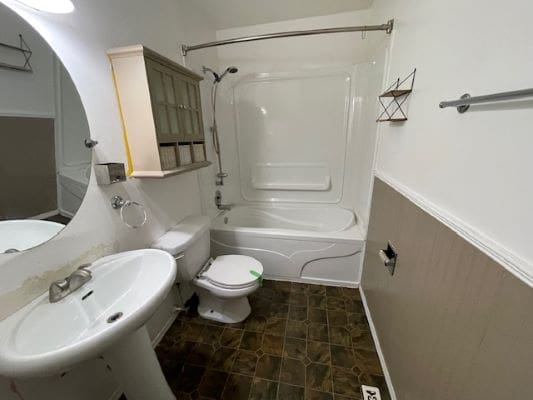 White bathroom with shower and pedestal sink.