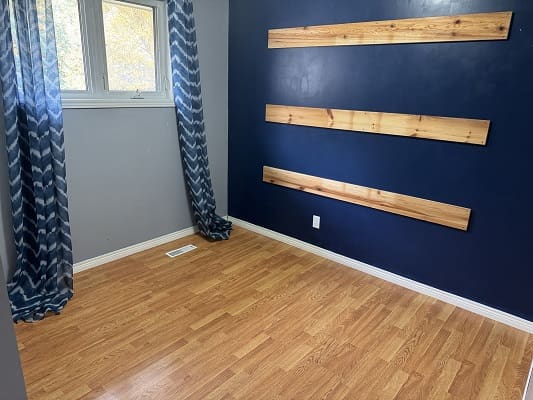 Room with blue accent wall and wood floor.