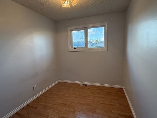 Small empty room with wooden floor, window.