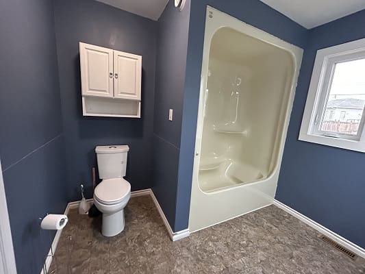 Blue bathroom with toilet and shower.