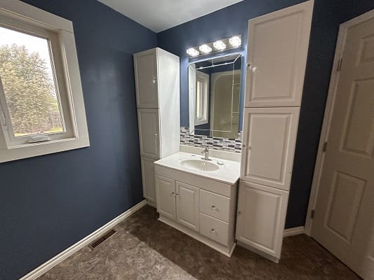 Blue bathroom with white vanity and cabinets.