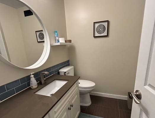 Small modern bathroom with round mirror.