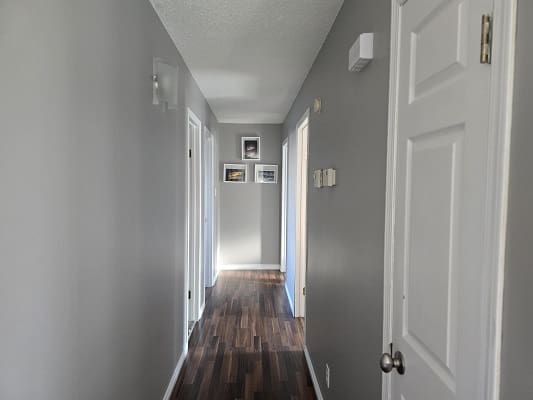 Narrow hallway with wooden floor and doors.