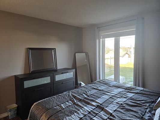 Bedroom with bed, dresser, and window view.