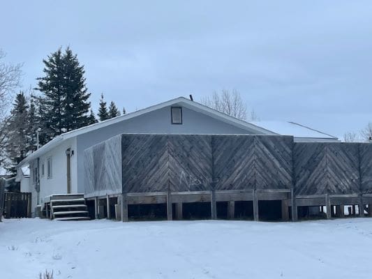 House with wooden fence in snowy landscape.