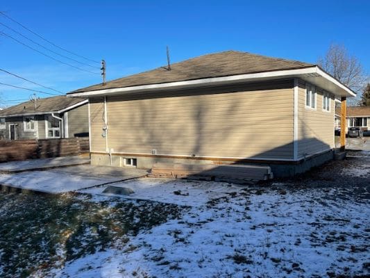 Side view of house with snowy ground.