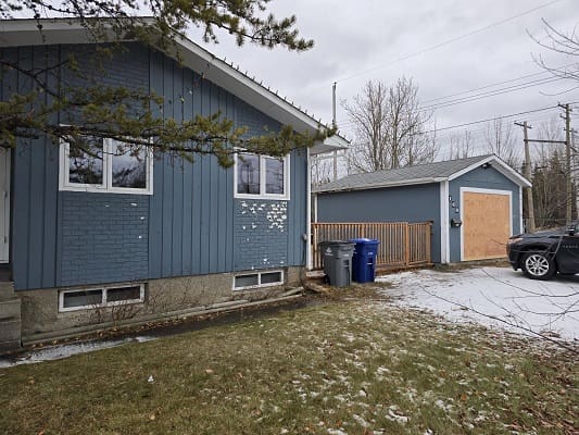 Blue house with garage in snowy yard.