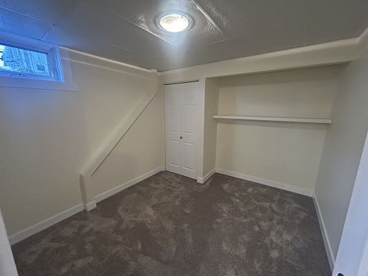 Small empty room with carpet and shelf.