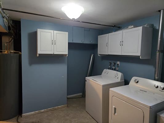 Laundry room with washer, dryer, and cabinets.