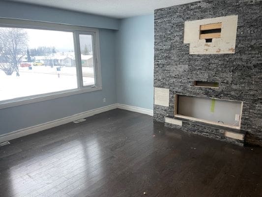 Empty room with unfinished fireplace and window.