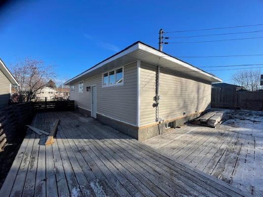 House with wooden deck under clear sky.