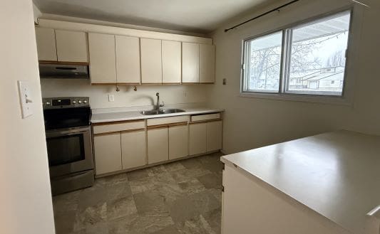 Small kitchen with white cabinets and appliances.
