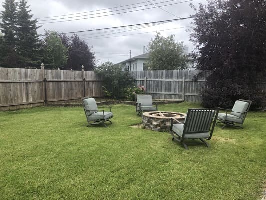 Backyard with chairs around a fire pit.