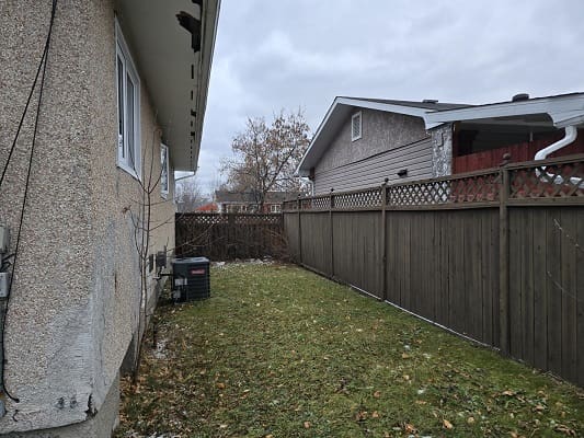 Narrow backyard with grass and wooden fence.