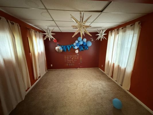 Empty room with birthday decorations and balloons.