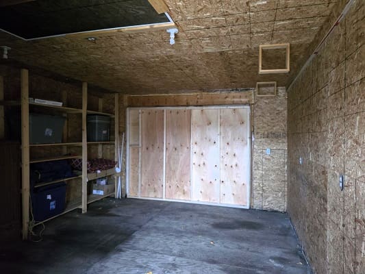 Wooden garage interior with storage shelves.