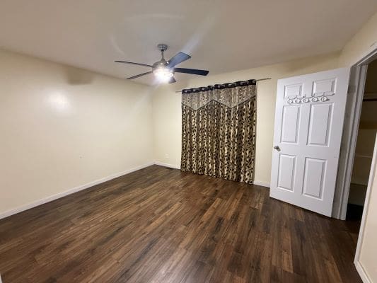 Empty room with wooden floor and curtains.
