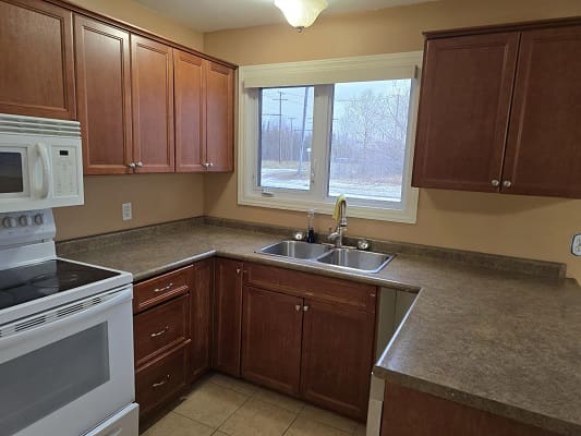 Kitchen with wooden cabinets and large window.