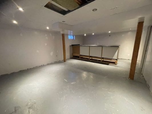 Unfinished basement with exposed ceiling and lighting.