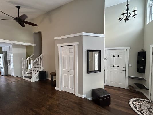 Spacious living area with staircase and chandelier.