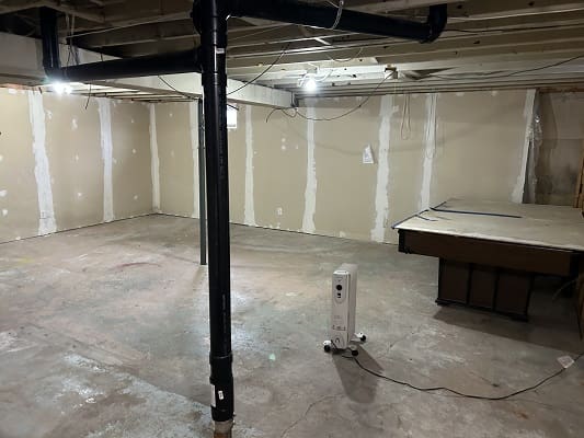 Unfinished basement with heater and pool table.