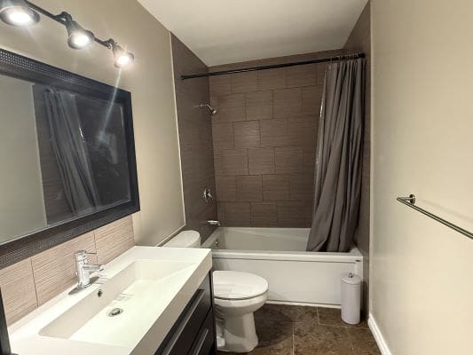 Modern bathroom with bathtub and large mirror.