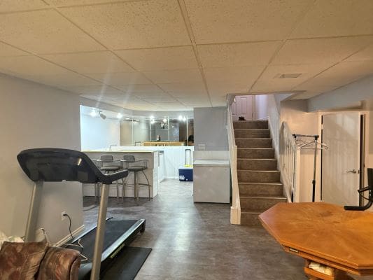 Basement with treadmill and bar area.