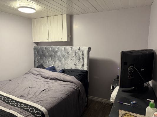 Small bedroom with bed and television.