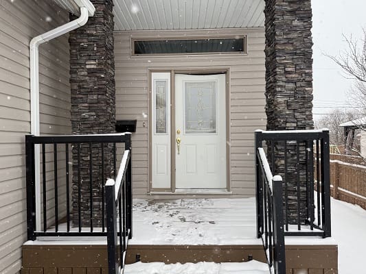 Snowy entrance with stone pillars and door.