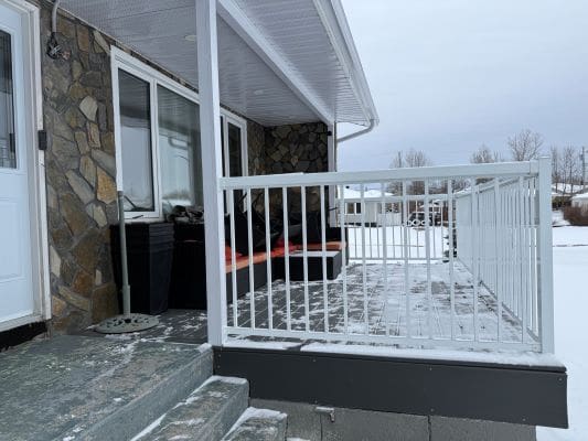 Snow-covered porch with stone wall exterior.