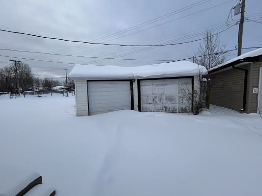 Snow-covered garage and landscape under cloudy sky.