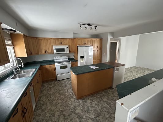 Spacious kitchen with wooden cabinets and appliances.