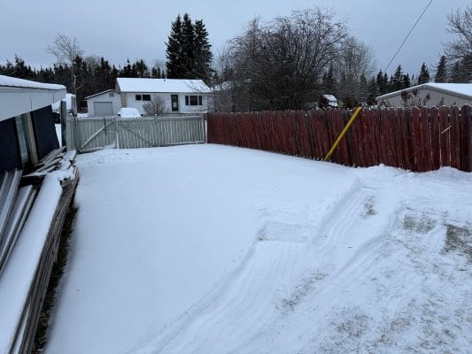 Snow-covered backyard with wooden fences.