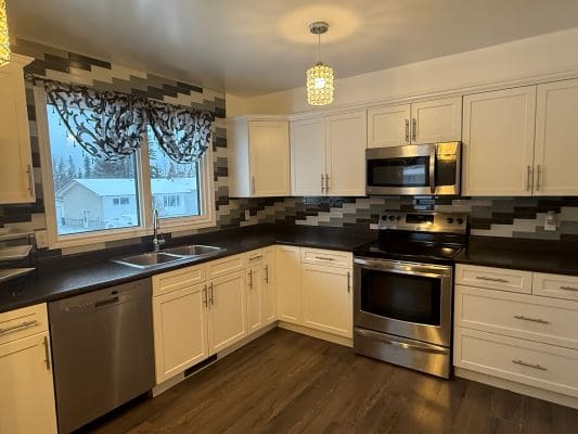 Modern kitchen with white cabinets and appliances.