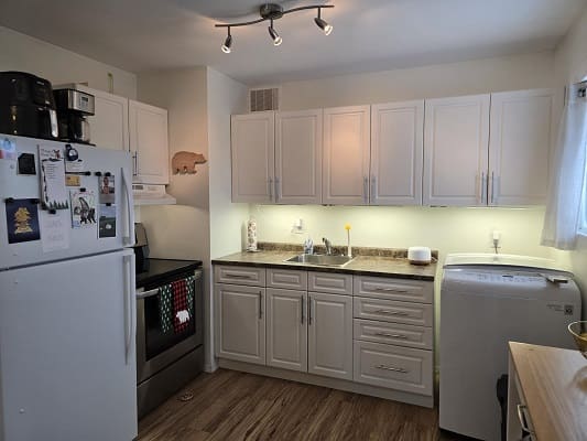 Modern kitchen with white cabinets and appliances.