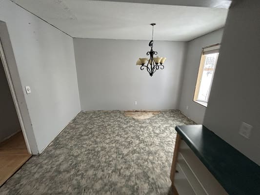 Empty room with chandelier and patterned floor.