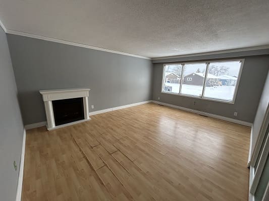 Empty room with fireplace and large window.