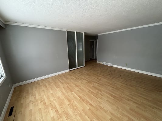 Empty room with wooden floor and gray walls.
