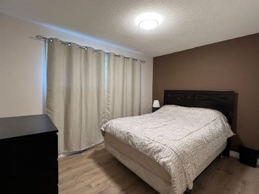 Bedroom with bed, dresser, and curtains.