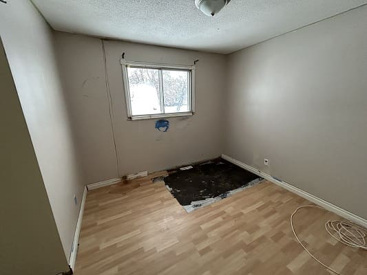 Empty room with damaged floor and window.