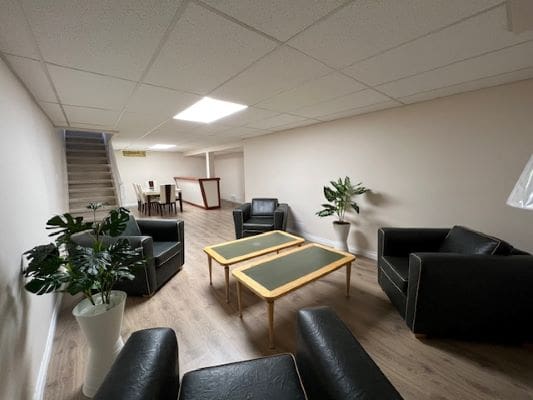 Basement lounge with black chairs and tables.