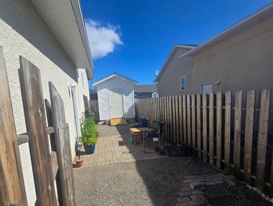 Narrow backyard with shed and patio furniture.