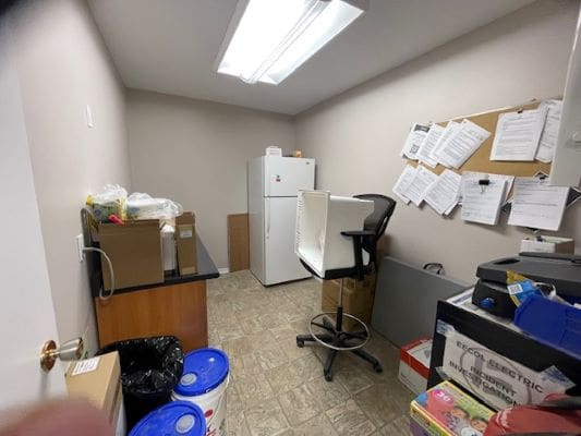 Small office storage room with refrigerator.